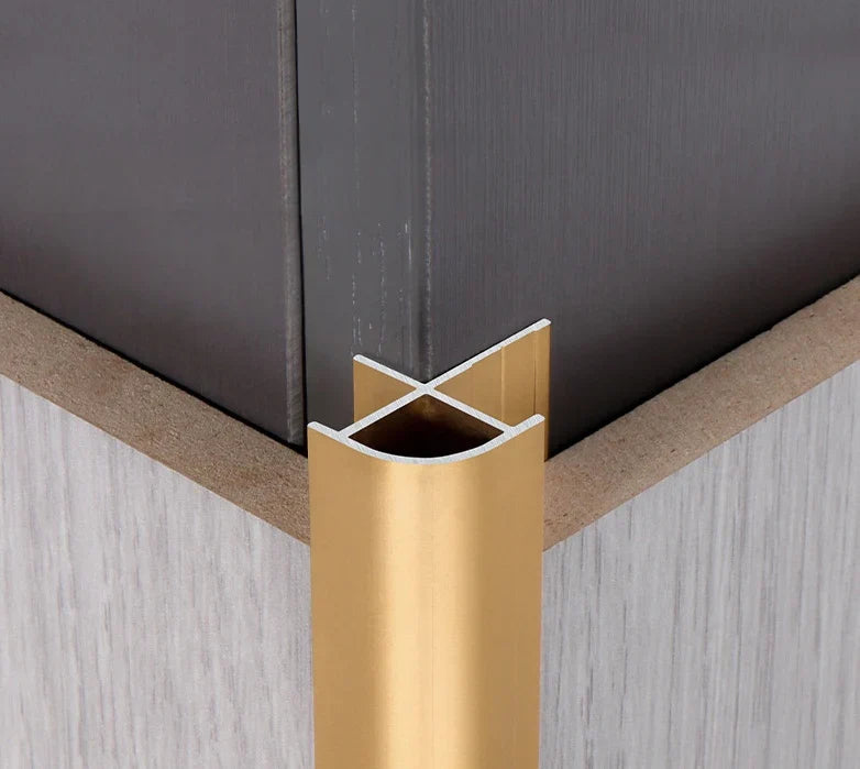 Gold aluminum wall panel outside corner trim installed on interior wall, providing a clean, durable metal edge finish for modern wall panels
