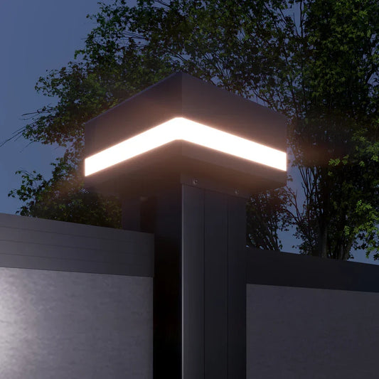 Illuminated LED cap installed on a dark composite fence post at dusk