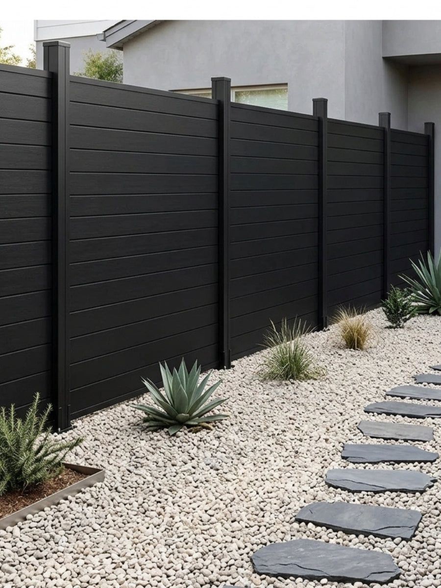 Black aluminum fence panels beside a white gravel path with drought-tolerant plants
