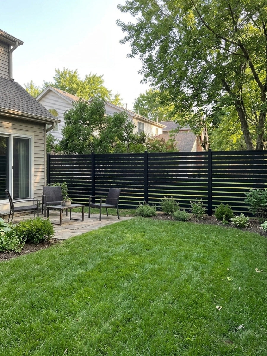 Black open slat aluminum fence enclosing a landscaped backyard lawn and patio