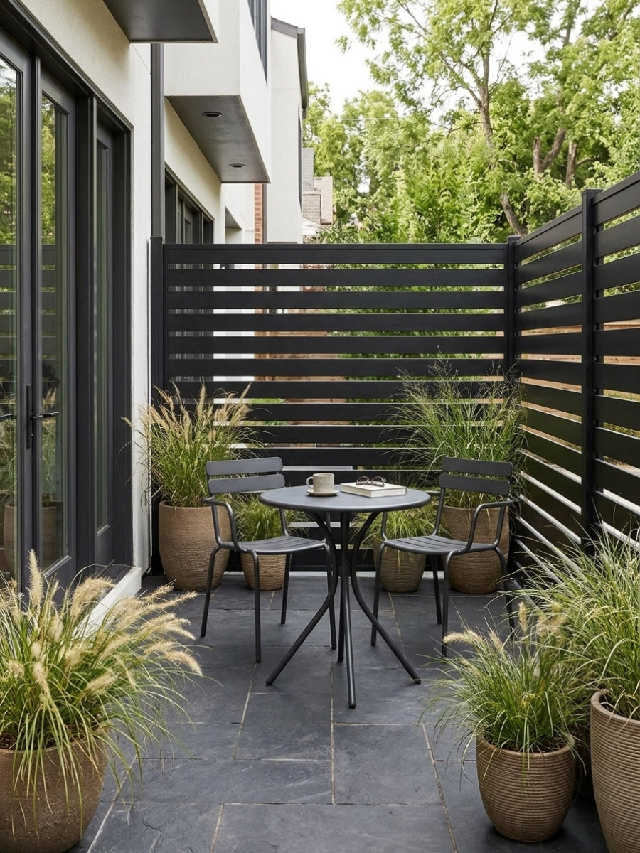 Black aluminum open slat fence creating privacy around a small patio dining area