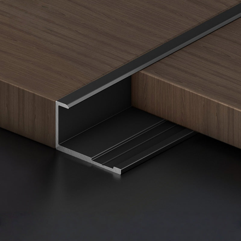 Black aluminum wall panel trim end cap installed on wood panels, durable metal edge strip for clean panel edges and modern interior wall finishing